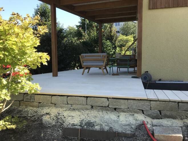 Überdachte Terrasse mit hellem Holzdeck und Sitzplatz